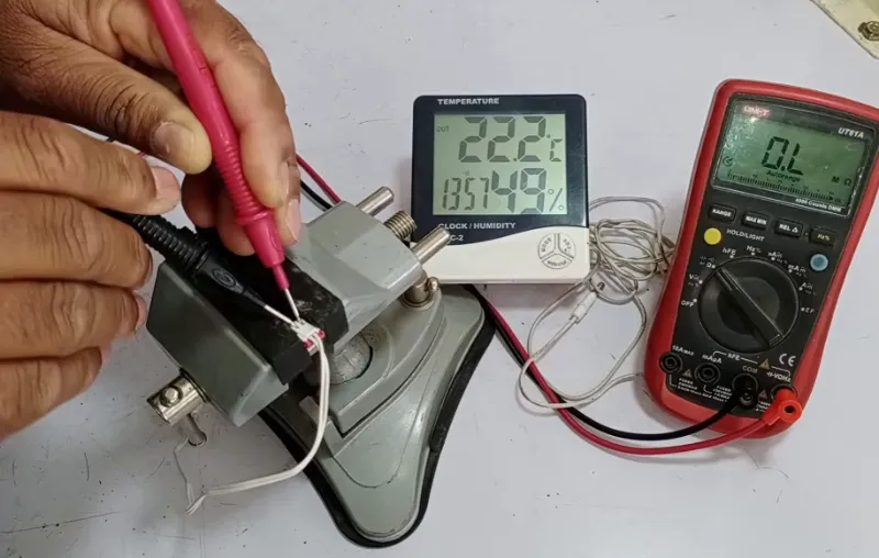 Technician testing an appliance electrical component with a multimeter during a repair diagnosis.